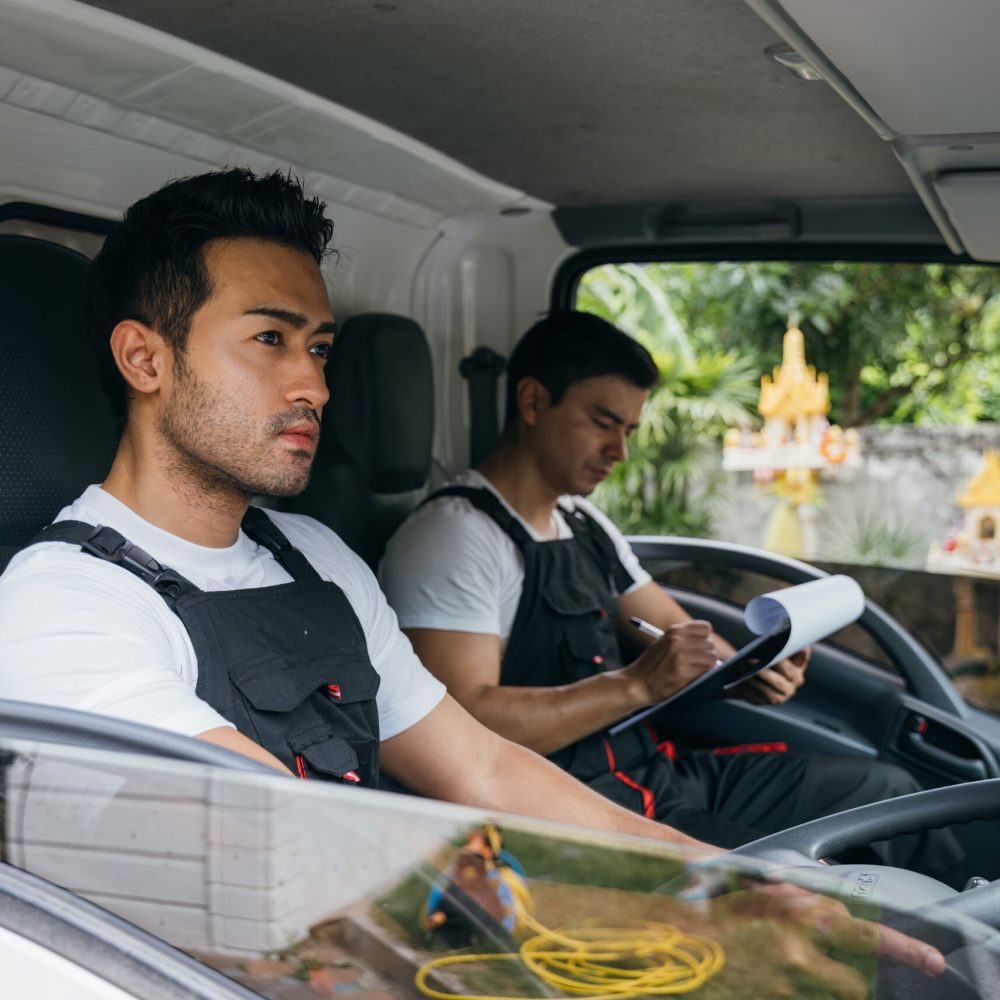 Transporting furniture, Mover workers driving truck for relocati Truck driver and mover workers for relocation service. Ethnic diversity in the team delivering and unloading furniture. Smiling employees in uniform. House moving service concept.